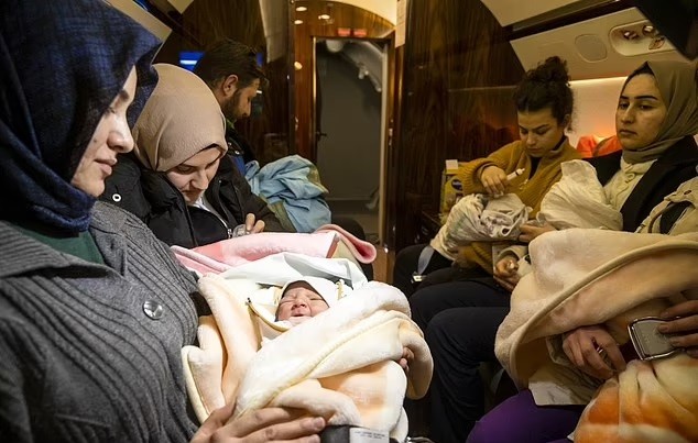 Các bé sơ sinh nằm trong vòng tay của lực lượng cứu hộ trên máy bay và được quấn nhiều tấm chăn để tránh bị lạnh.