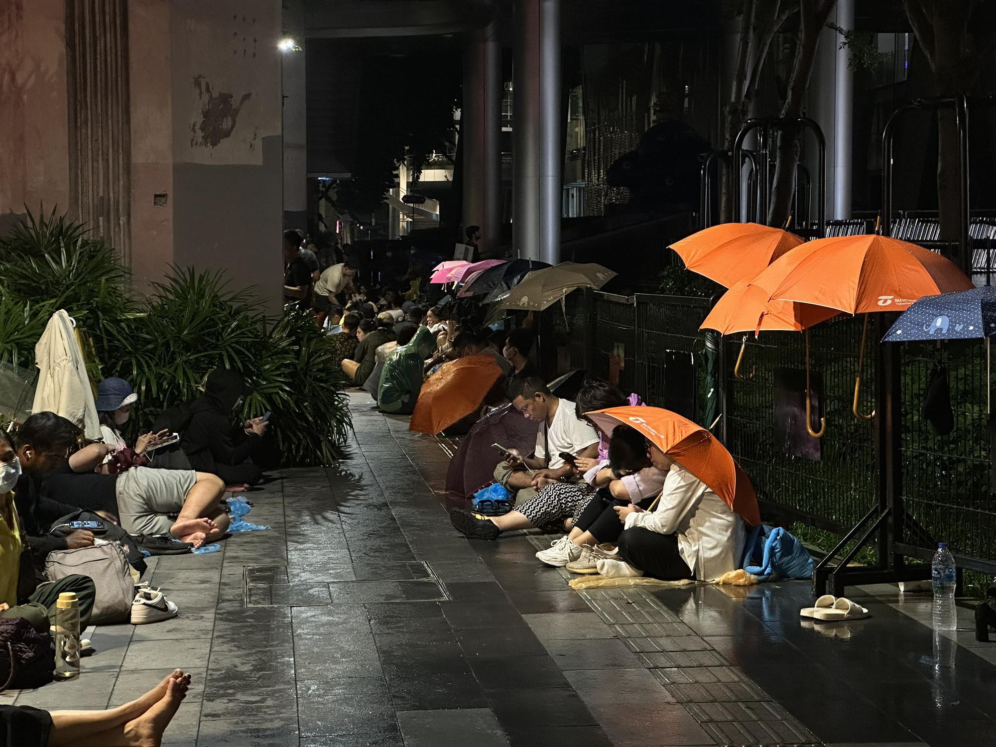 人們在雨中等待世界中心購物中心 iPhone 促銷活動（泰國）