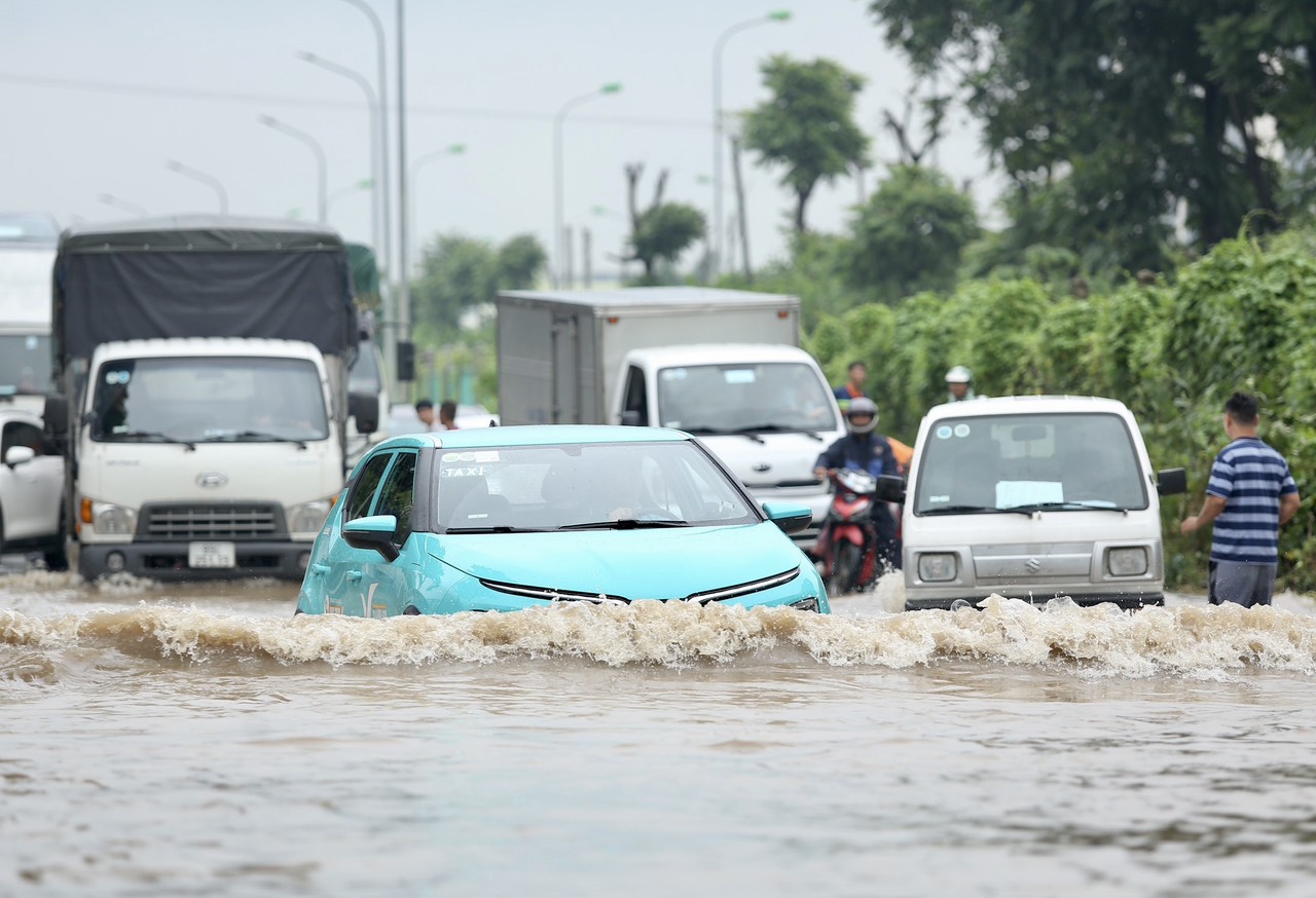 Đại lộ Thăng Long ngập sâu sau nhiều giờ mưa tạnh, người dân chật vật đi qua - Ảnh 1.