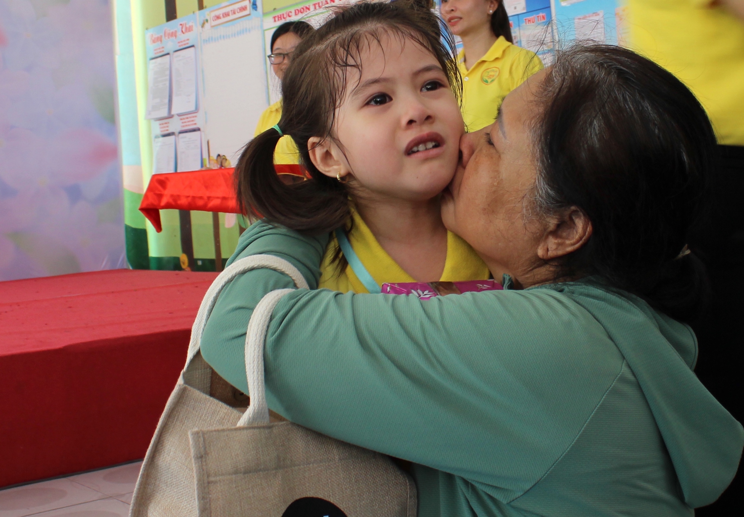 Giọt nước mắt của bé Nguyễn Quốc Kim Ngân (người về thứ tư) trong vòng tay cô giáo và vòng tay bà của mình