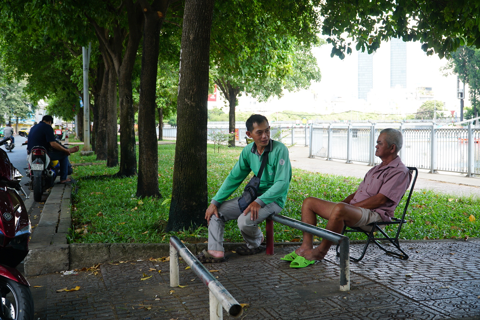 Ông Lâm Hùng Anh (bên phải) mỗi ngày đều ngồi dưới những gốc cây để tránh nóng