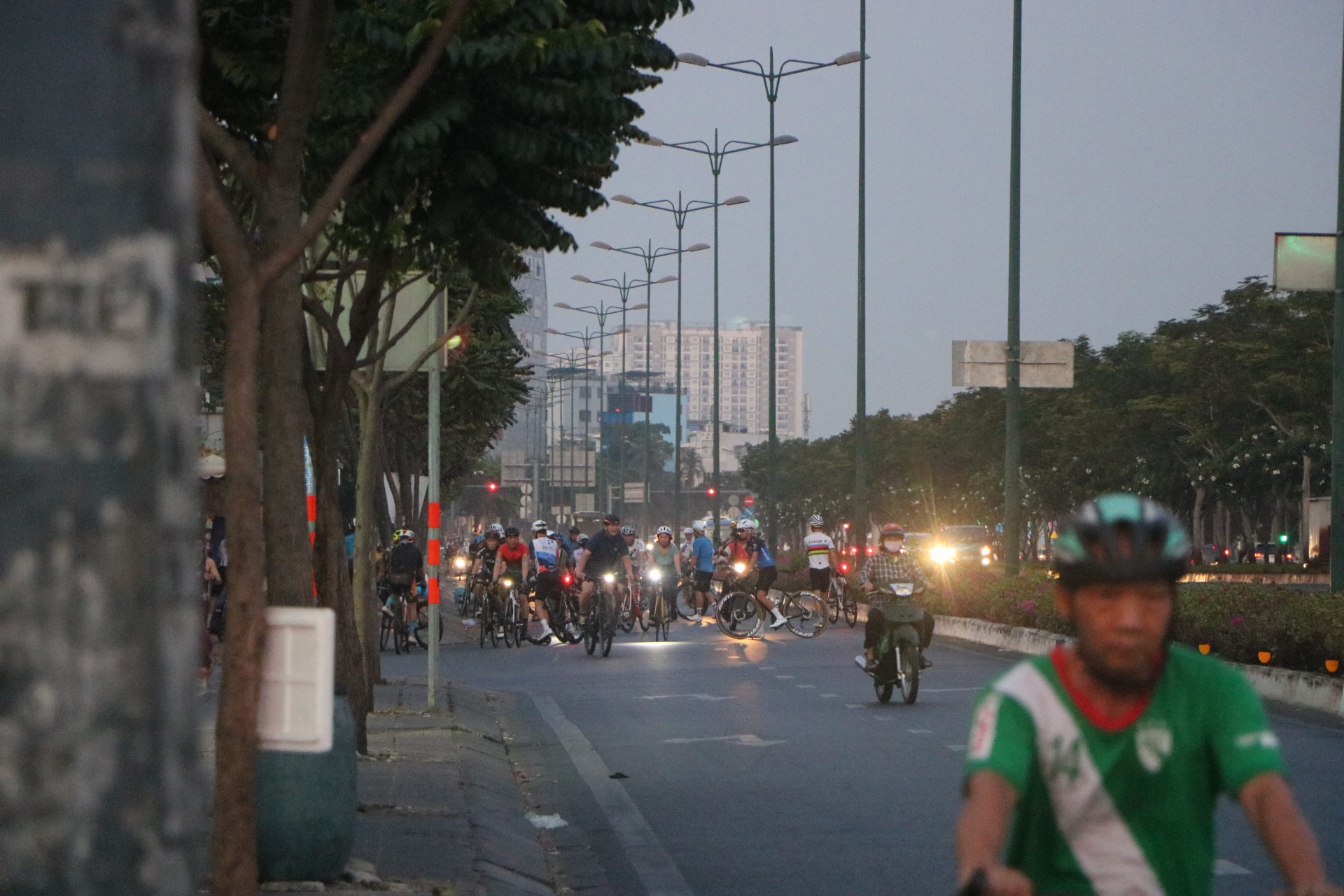 Hơn chục người đi xe đạp trong làn ô tô vội ôm xe qua dải phân cách, leo vào trong vỉa hè quay đầu đi ngược chiều
