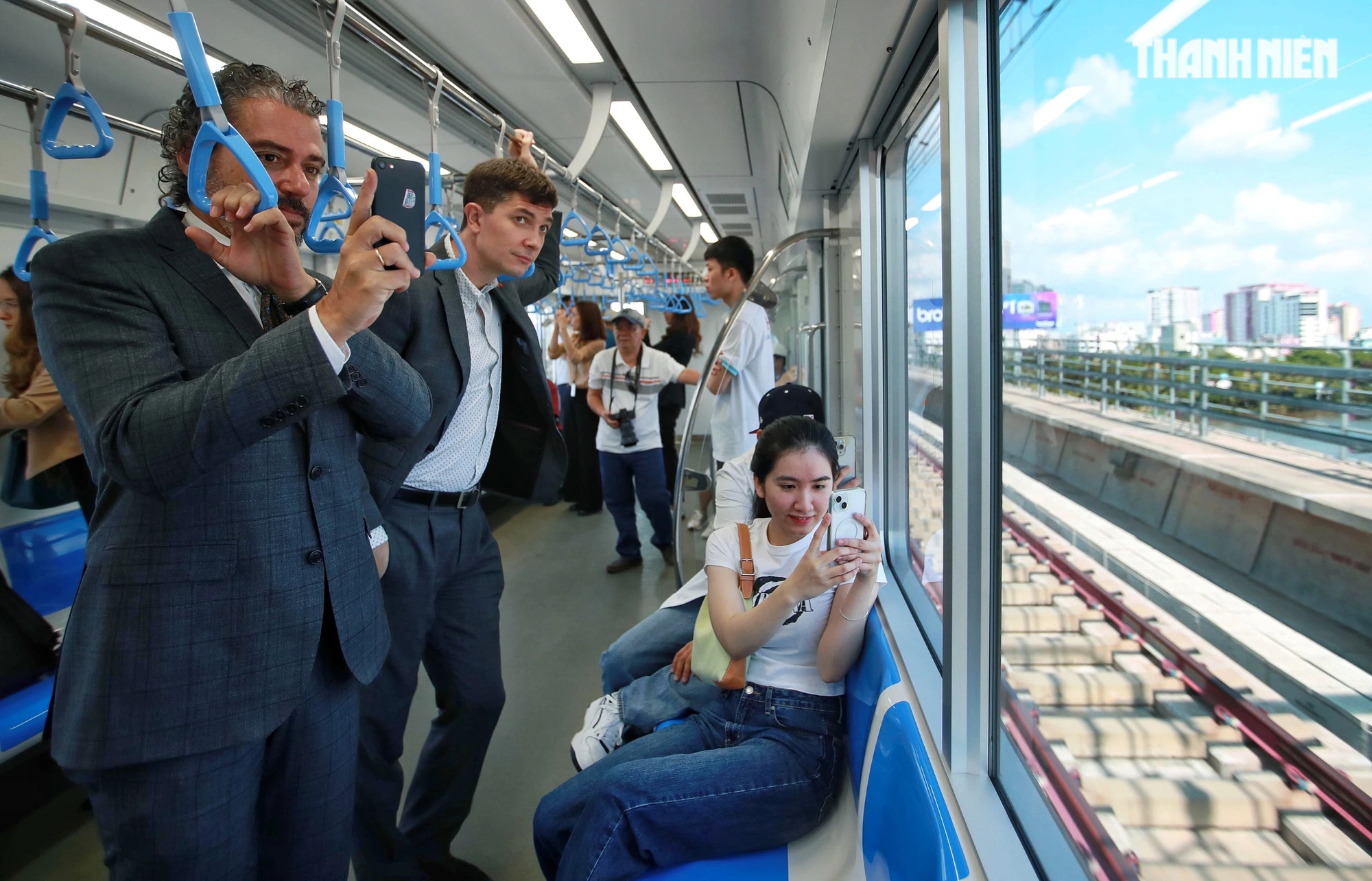 Những vị khách hào hứng dùng điện thoại ghi lại quang cảnh thành phố khi đoàn tàu metro di chuyển qua các nhà ga trên cao