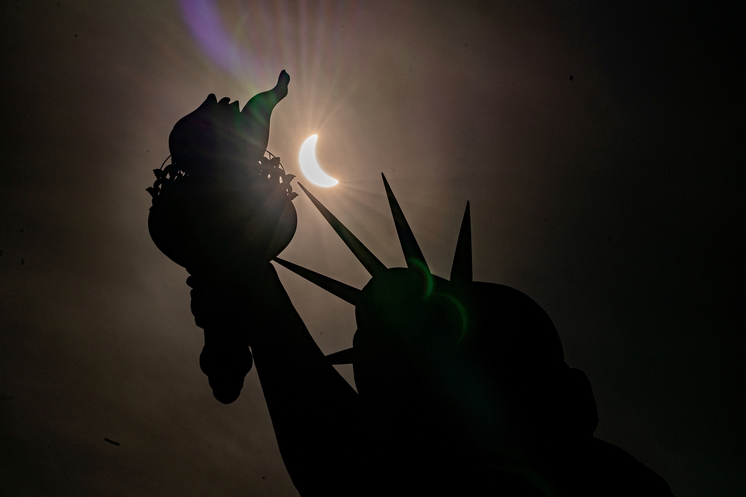 Mặt trăng che gần hết mặt trời trong hình ảnh được chụp gần tượng Nữ thần Tự do tại New York (Mỹ)