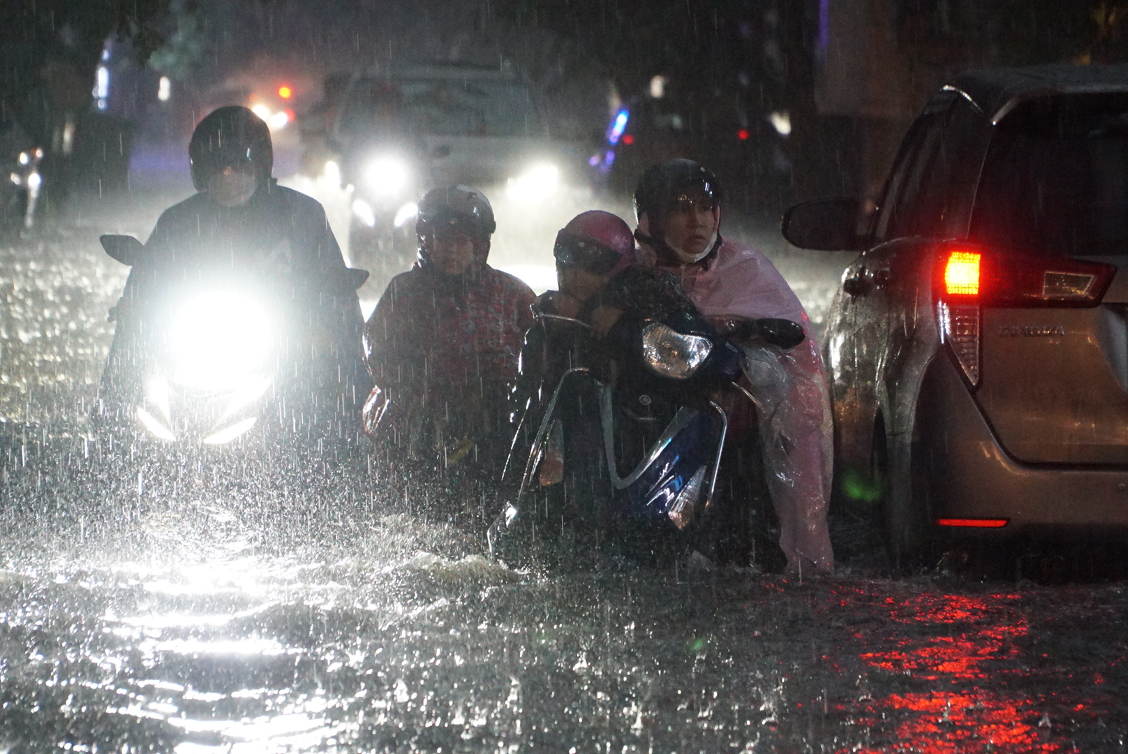 Nhiều người dân có xe chết máy phải đẩy bộ trong mưa và nước ngập trên đường Quốc Hương