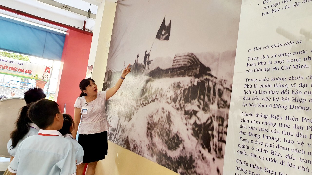 Cô Tạ Thị Thái, Hiệu trưởng, cùng các em học sinh bên tấm ảnh lịch sử chiến thắng Điện Biên Phủ được treo ở vị trí trang trọng ở sảnh của nhà trường