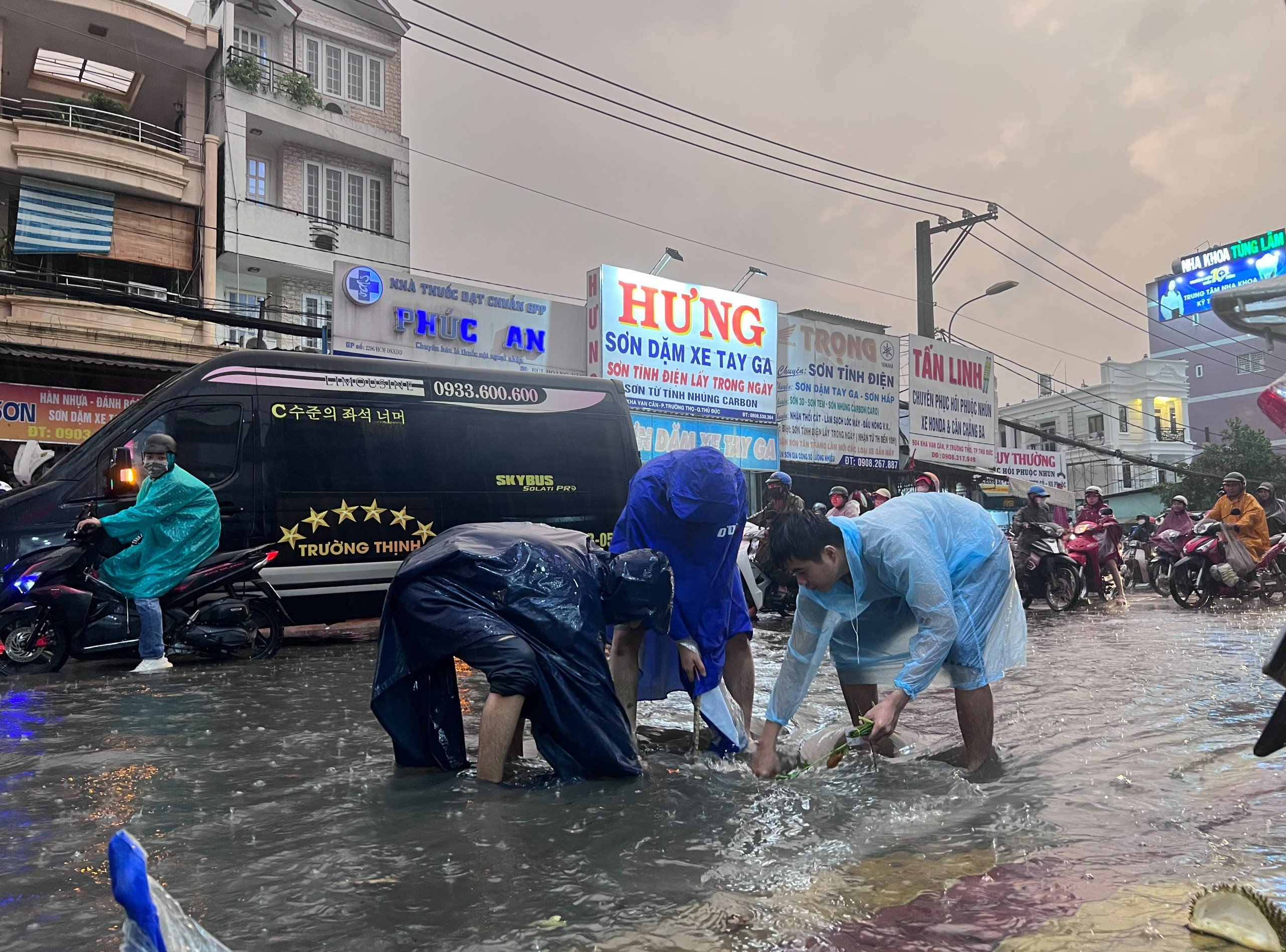 Những người dân xung quanh khu vực chợ Thủ Đức đội mưa dọn rác làm tắc nghẽn cống