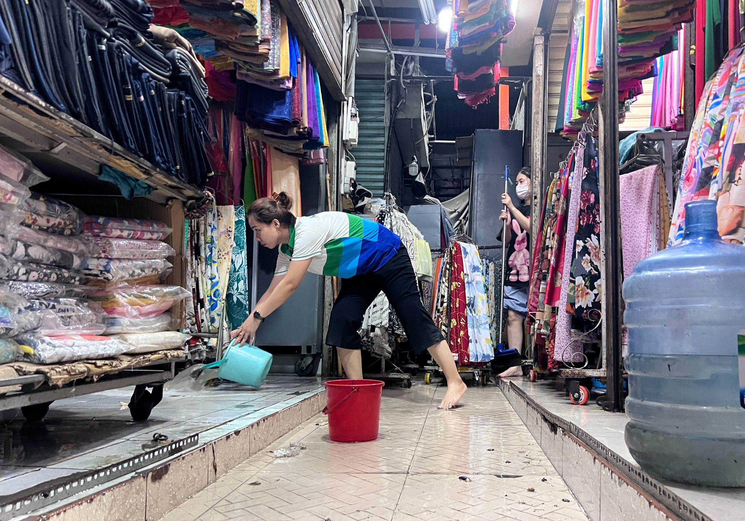 Một tiểu thương ở chợ Thủ Đức dọn dẹp sau khi bị nước ngập tràn vào cửa hàng làm ướt hàng hóa.