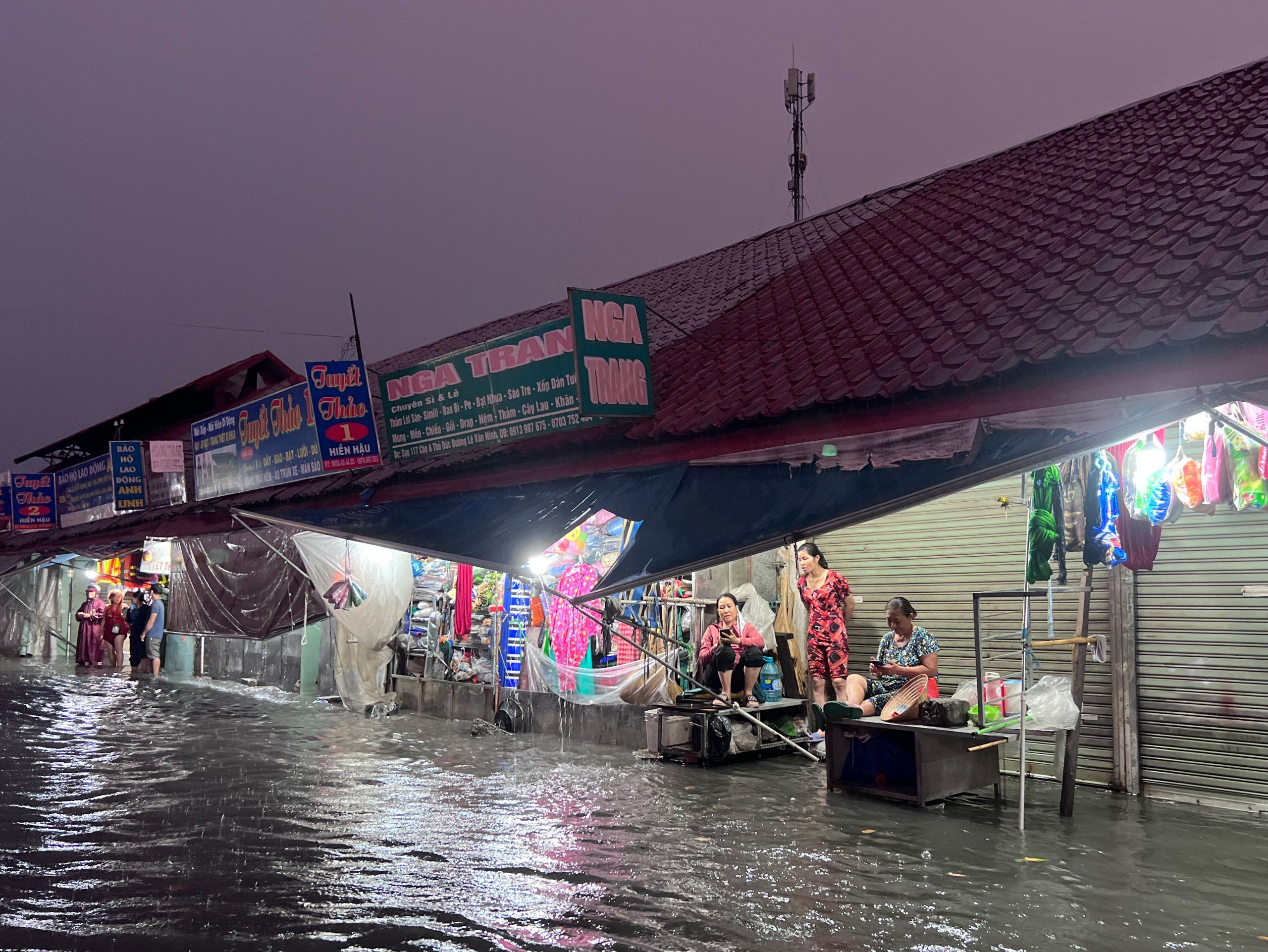 Tiểu thương chợ Thủ Đức ngồi bó gối, chưa thể di chuyển về nhà vì mưa lớn, nước ngập sâu