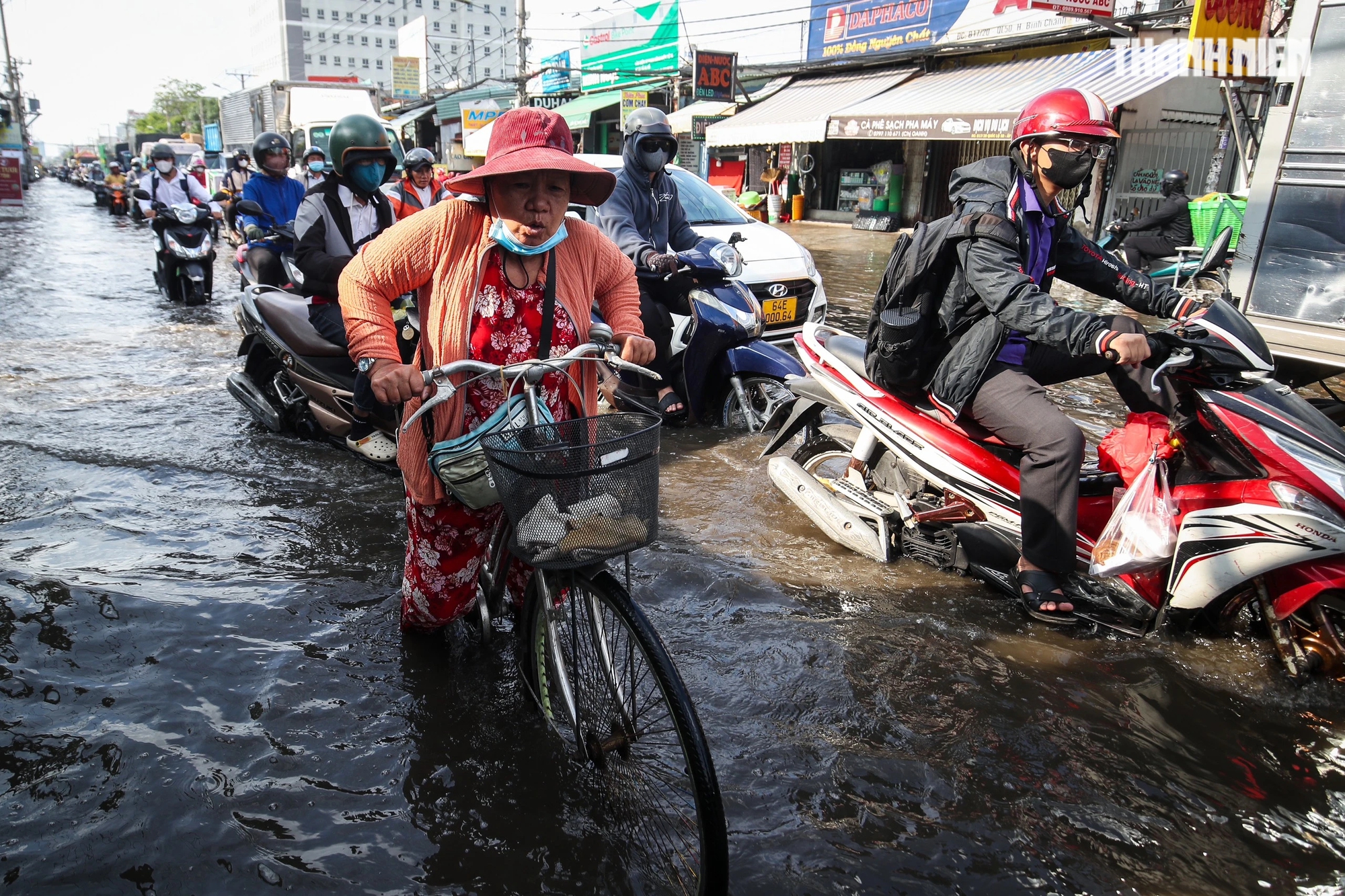 Người lao động vất vã di chuyển qua đoạn đường ngập nước