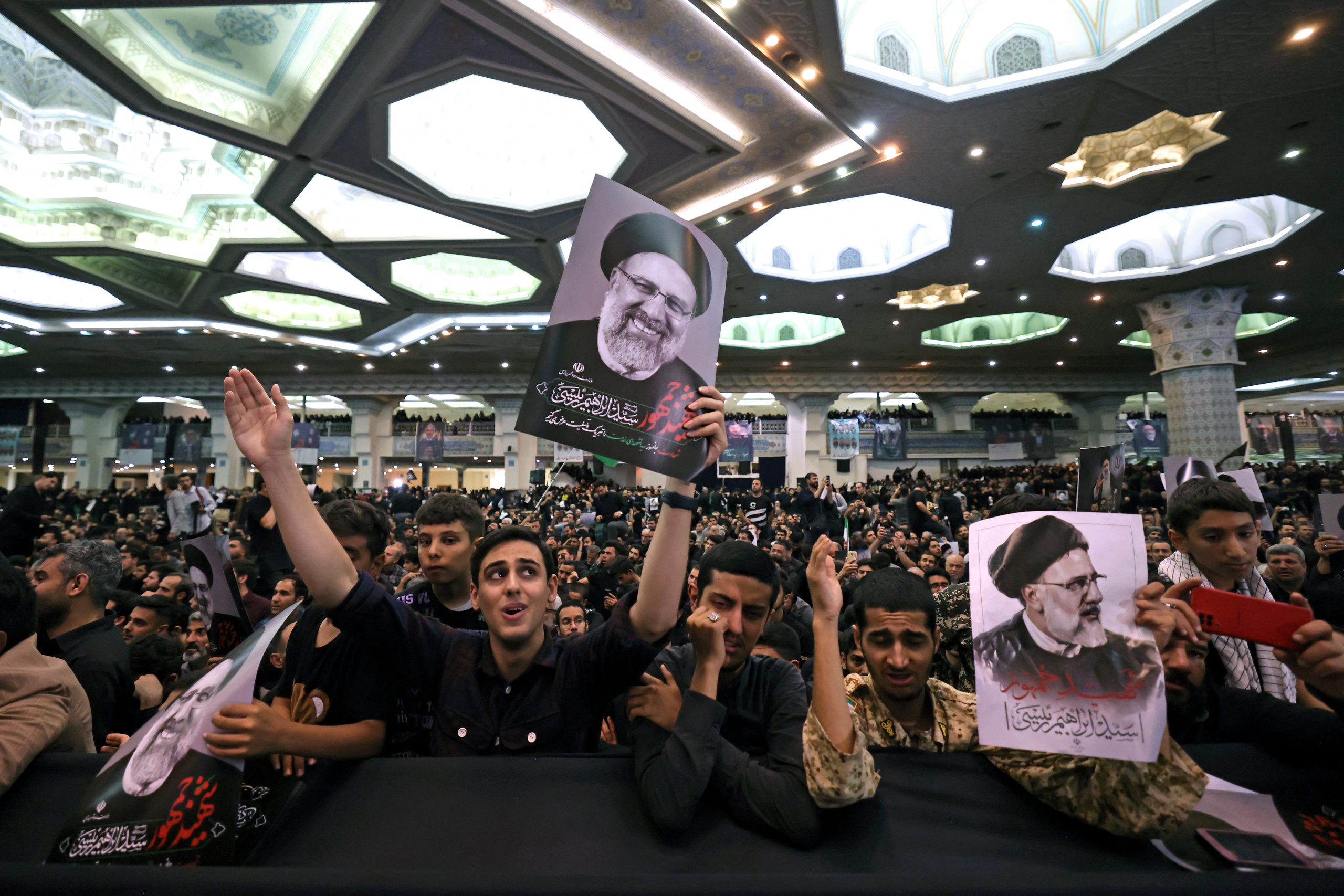 Những người dân Iran cầm di ảnh của cố Tổng thống Ebrahim Raisi