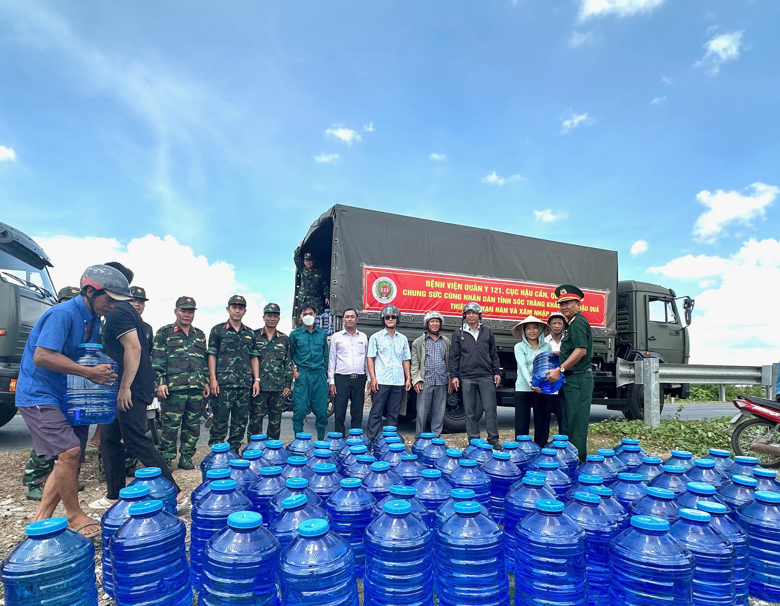 Bệnh viện Quân y 121 đưa nước uống tinh khiết đến với người dân vùng hạn mặn- Ảnh 1. Đại tá Lê Văn Hiền, Chính ủy Bệnh viện Quân y 121 (bìa phải) tặng nước uống tinh khiết cho người dân Sóc Trăng