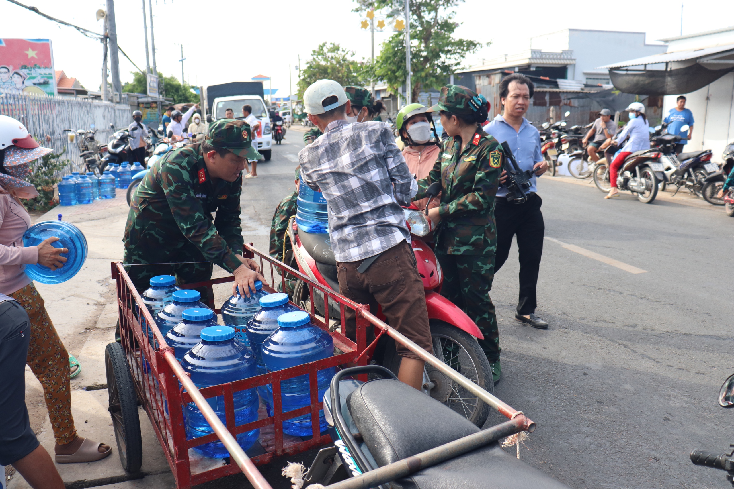 Bệnh viện Quân y 120 tặng nước uống tinh khiết cho người dân Gò Công Đông- Ảnh 1. Nhân viên bệnh viện hỗ trợ người dân mang nước về nhà