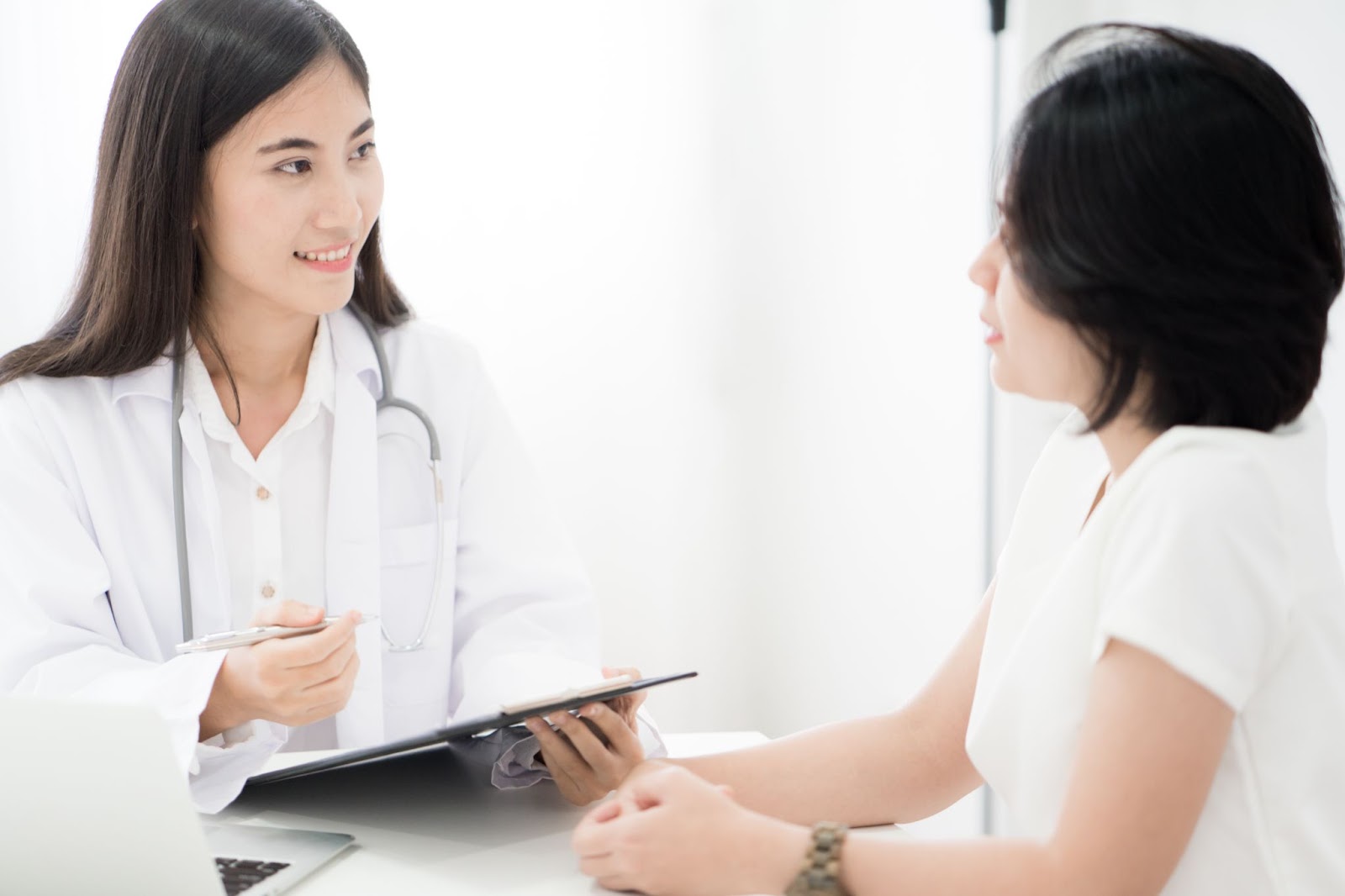 A doctor talking to a patient  Description automatically generated