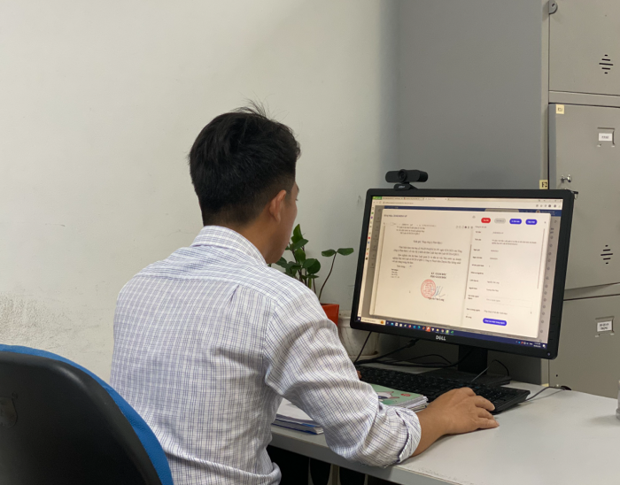 A person sitting at a desk using a computer  Description automatically generated