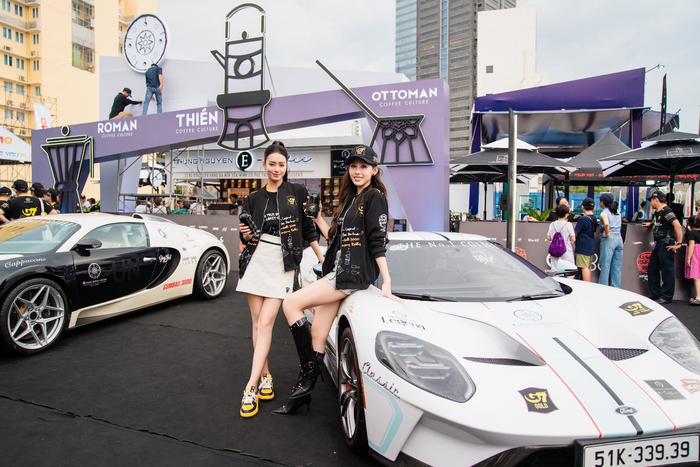 Two women posing for a picture next to a car  Description automatically generated