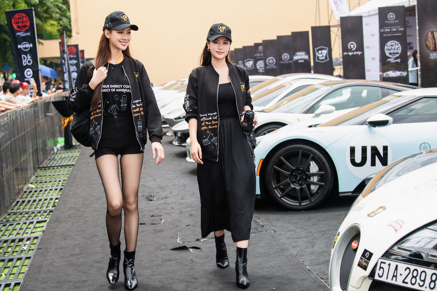 Two women walking down a street with cars in the background  Description automatically generated