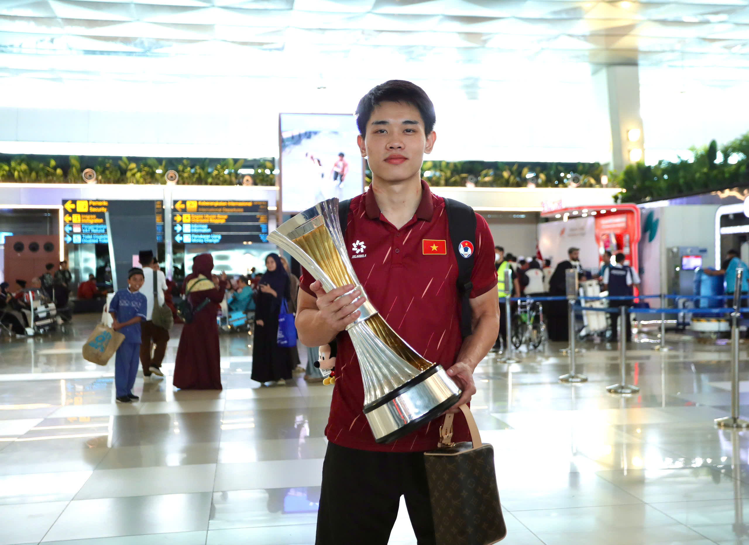 Dinh Bac “តស៊ូ” ដើម្បីដណ្ដើមពានរង្វាន់ អ្នកគាំទ្រឥណ្ឌូណេស៊ីបានសុំប័ណ្ណសម្គាល់ U.23 វៀតណាមនៅព្រលានយន្តហោះ - រូបថត ៦. Đình Bắc ‘khệ nệ’ cầm cúp, CĐV Indonesia xin chữ ký U.23 Việt Nam ở sân bay- Ảnh 6.