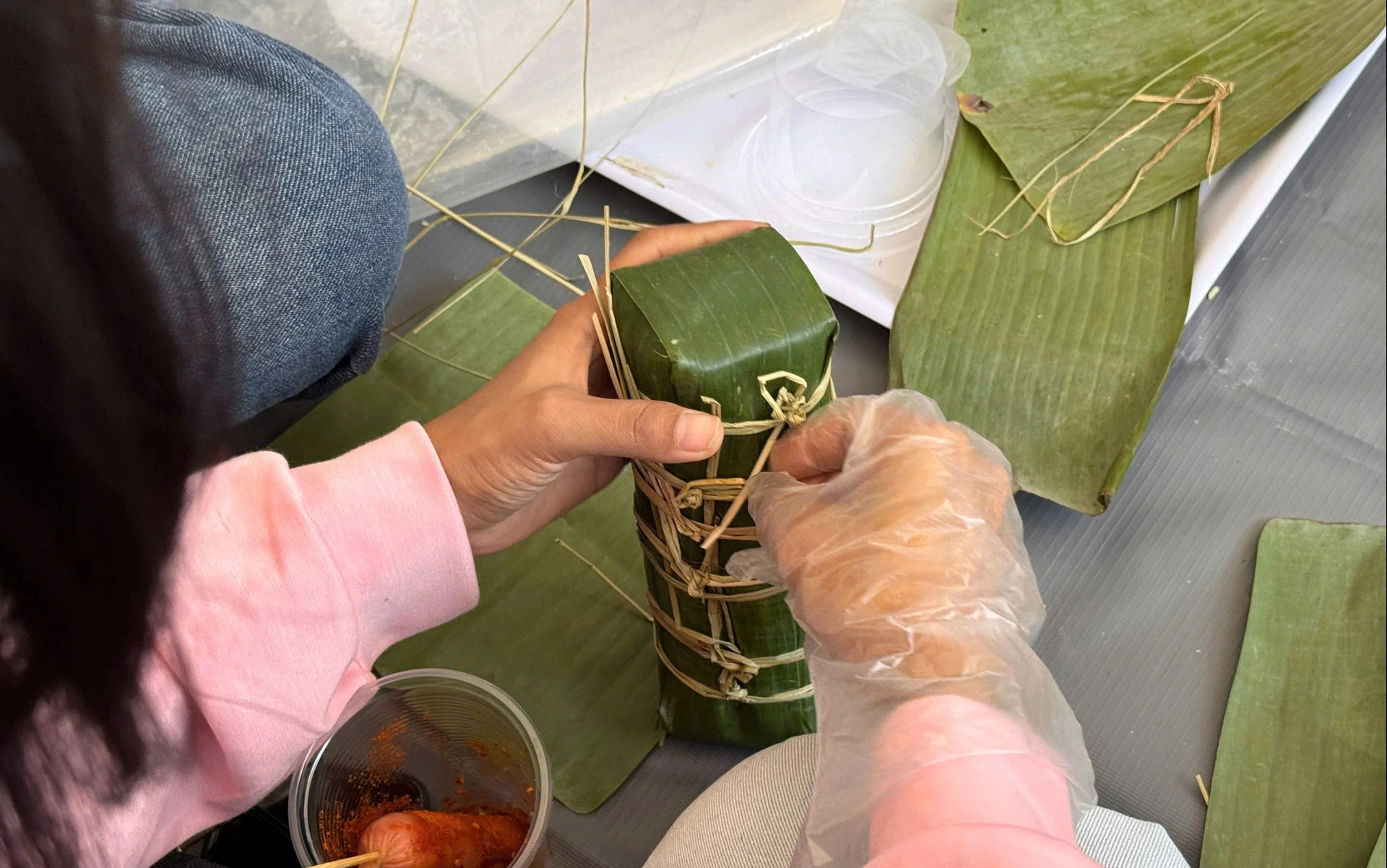 Sinh viên quốc tế lúng túng lần đầu gói bánh tét, đón Tết Việt giữa giảng đường - Ảnh 3.