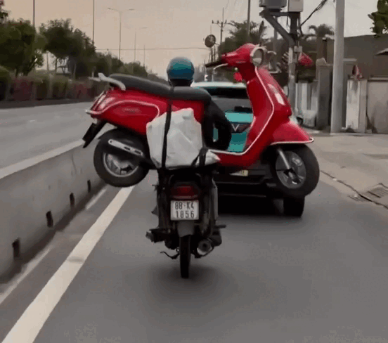 Người đ&agrave;n &ocirc;ng đi xe m&aacute;y chở theo một xe tay ga tr&ecirc;n y&ecirc;n xe ở quốc lộ 22 - Ảnh 1.