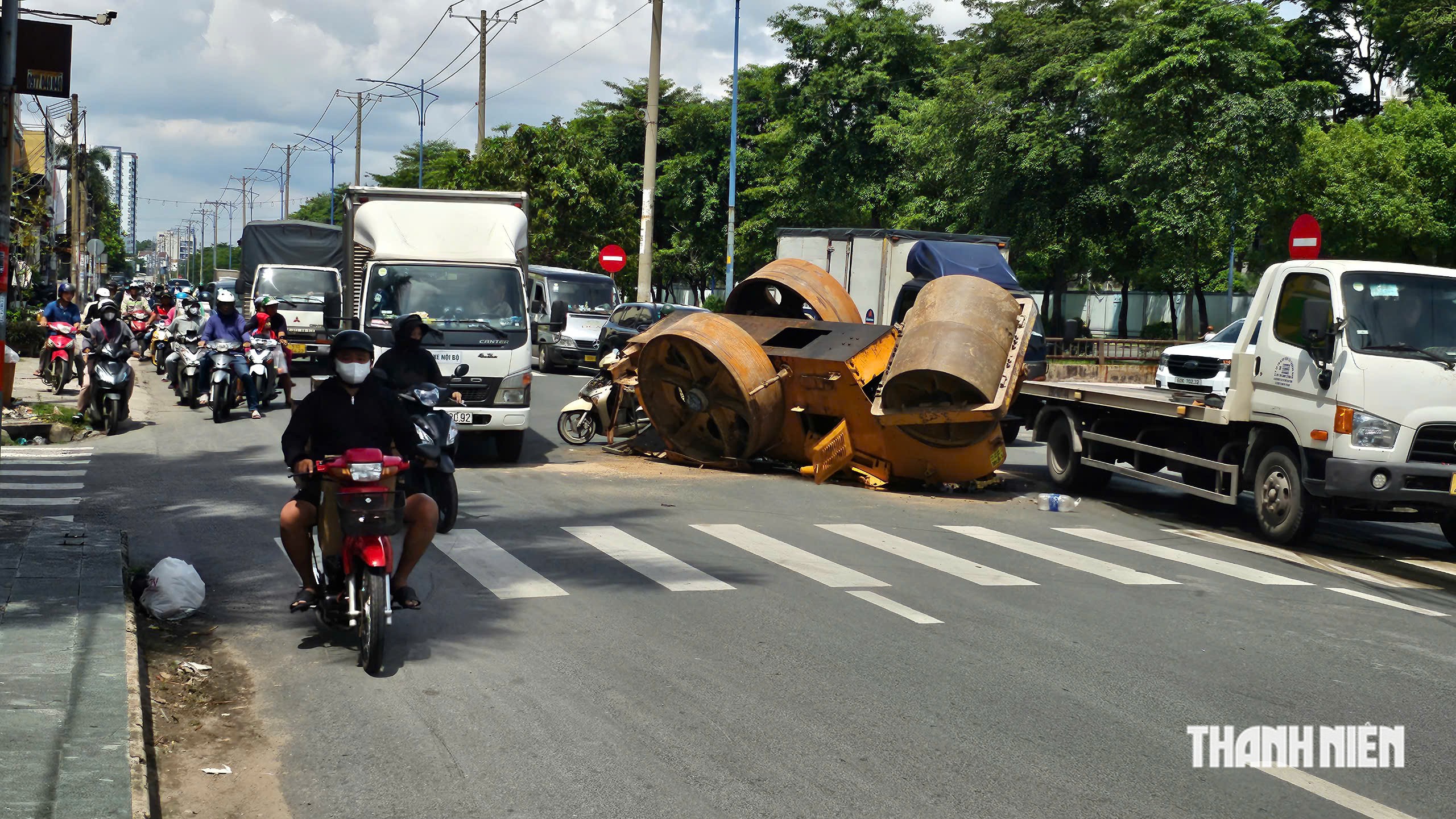 TP.HCM: Xe tải chở xe lu bị lật trên đường, 2 người thoát nạn trong gang tấc- Ảnh 1.