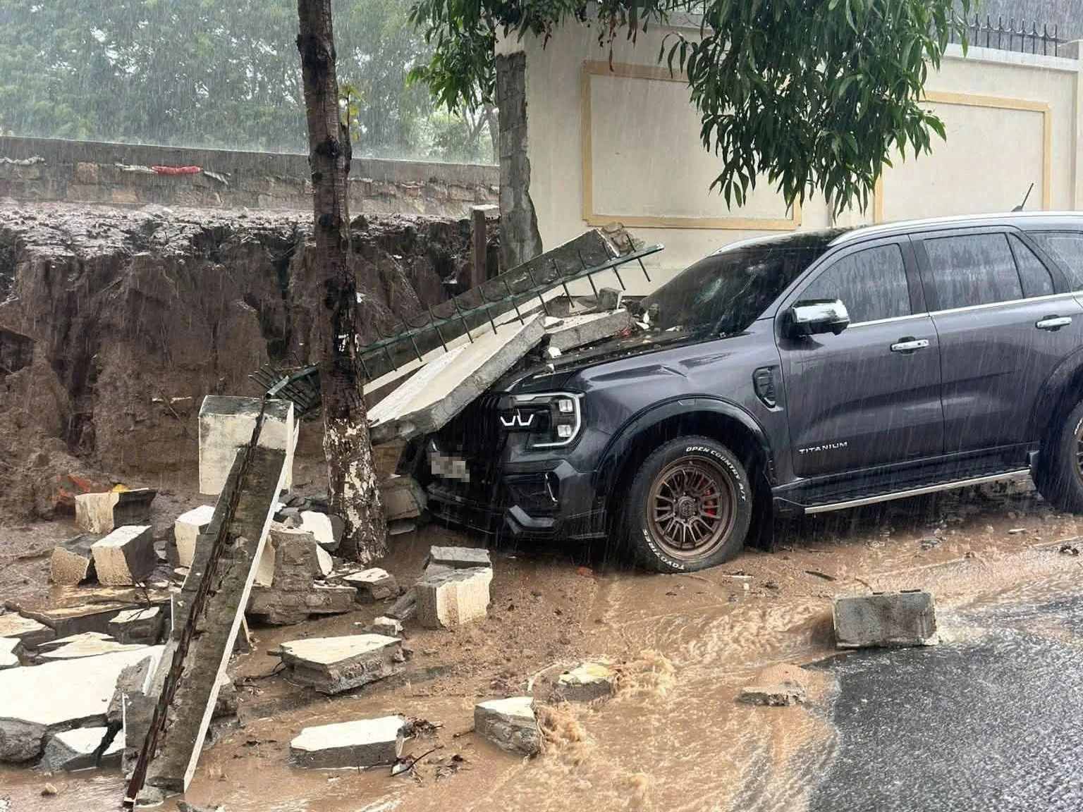 Khánh Hòa mưa lớn, tường rào bất ngờ đổ sập đè móp đầu ô tô Ford Everest - Ảnh 1.