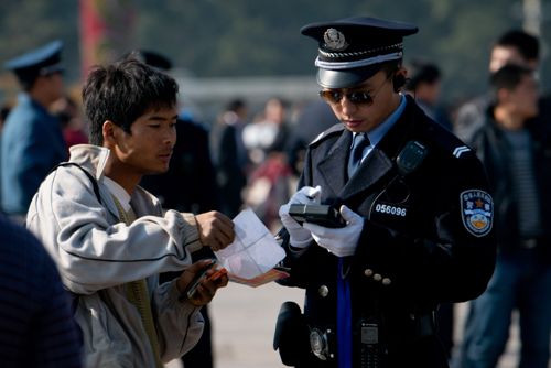 Một cảnh sát Trung Quốc kiểm tra giấy tờ của một người dân tại quảng trường Thiên An Môn - Ảnh: AFP