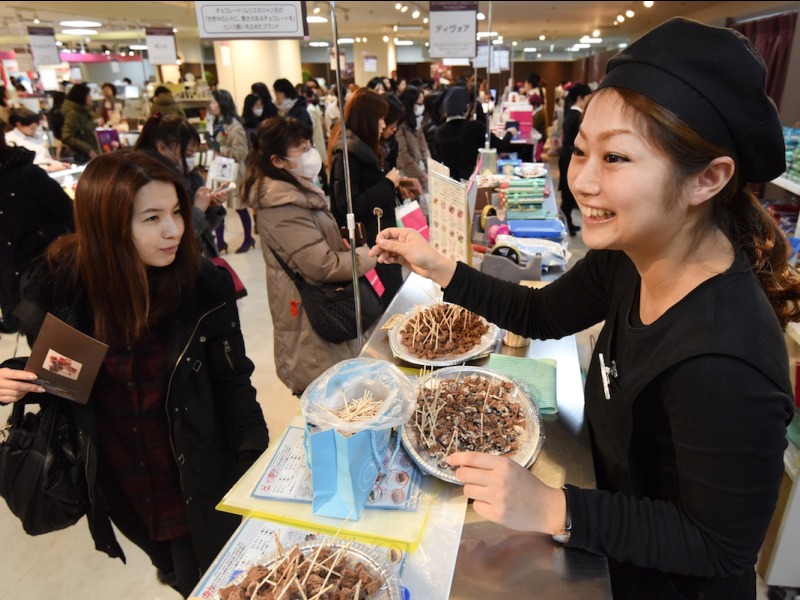 Một người bán hàng mời khách dùng thử sô cô la tại Tokyo (Nhật Bản) - Ảnh: AFP