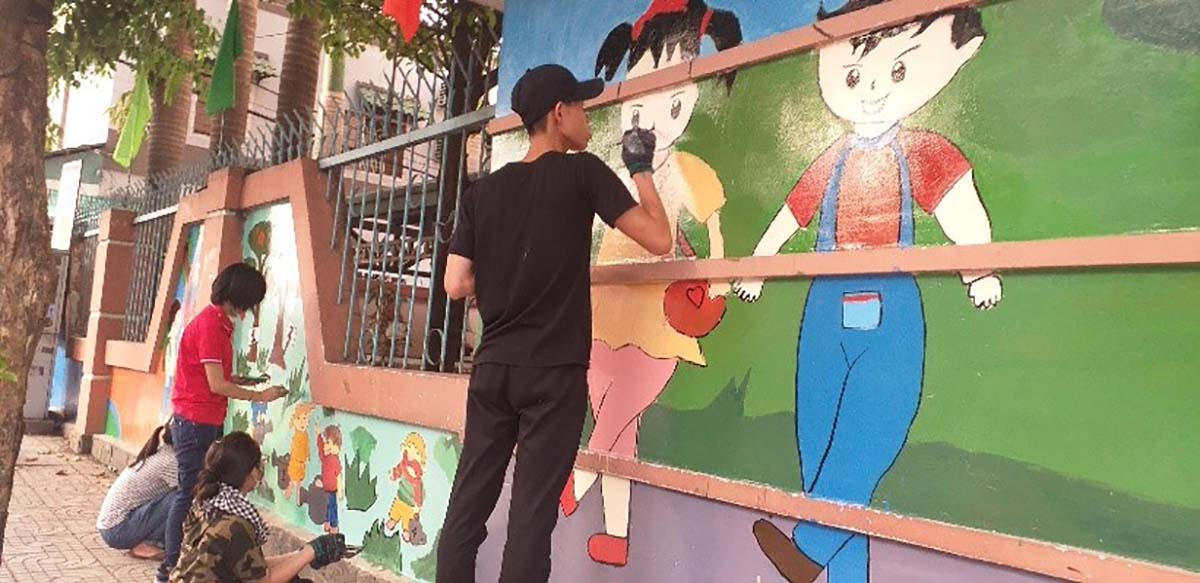 Các tình nguyện viên tham gia vẽ tranh tường bên ngoài một công trình trường học