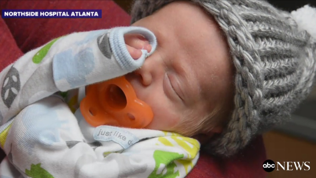  Một đứa trẻ sơ sinh ấm cúng trong chiếc mũ len do ông Moseley đan tặng - Ảnh: chụp video ABC News