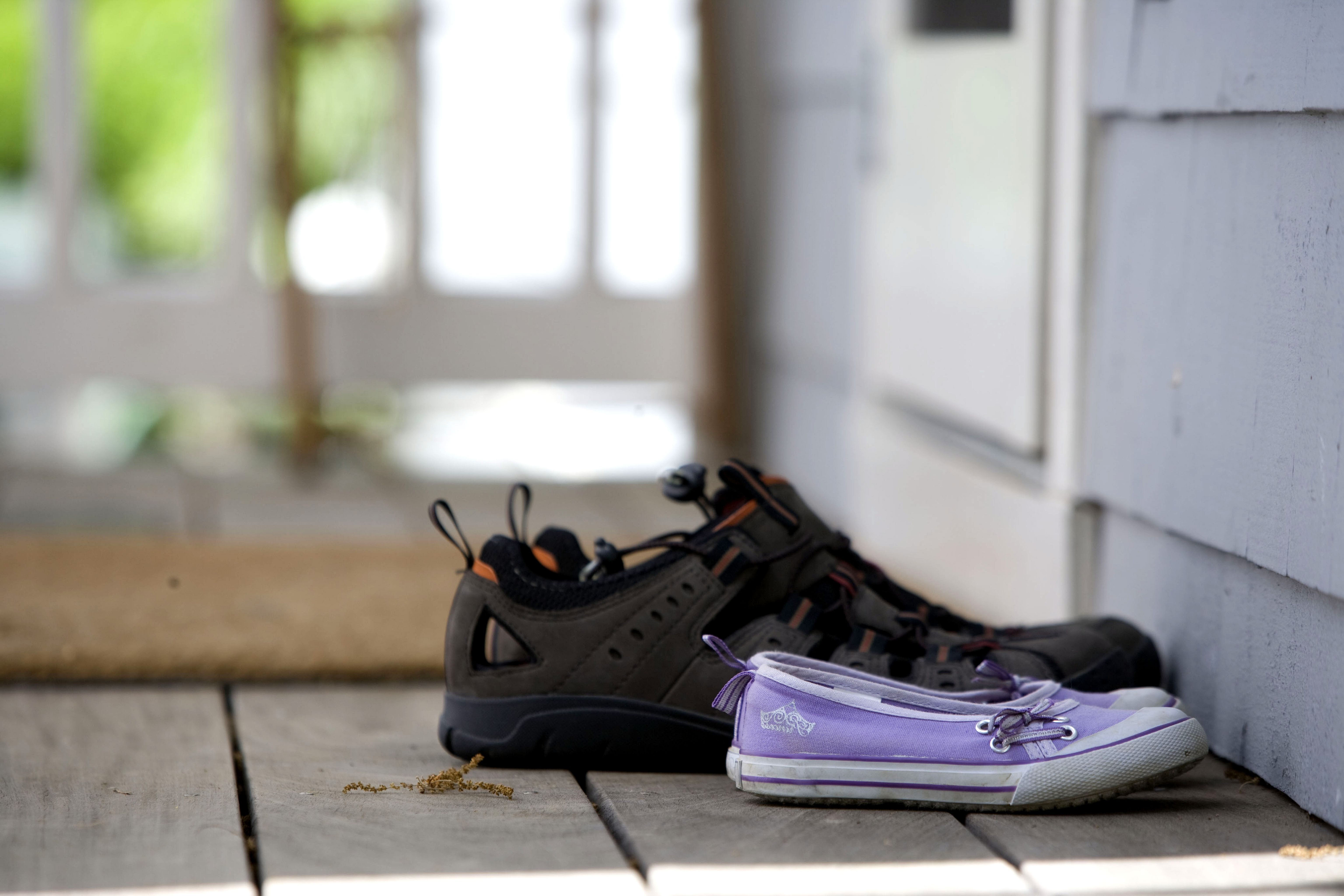 female-purple-and-male-brown-sports-shoes-at-the-front-door-to-the-house