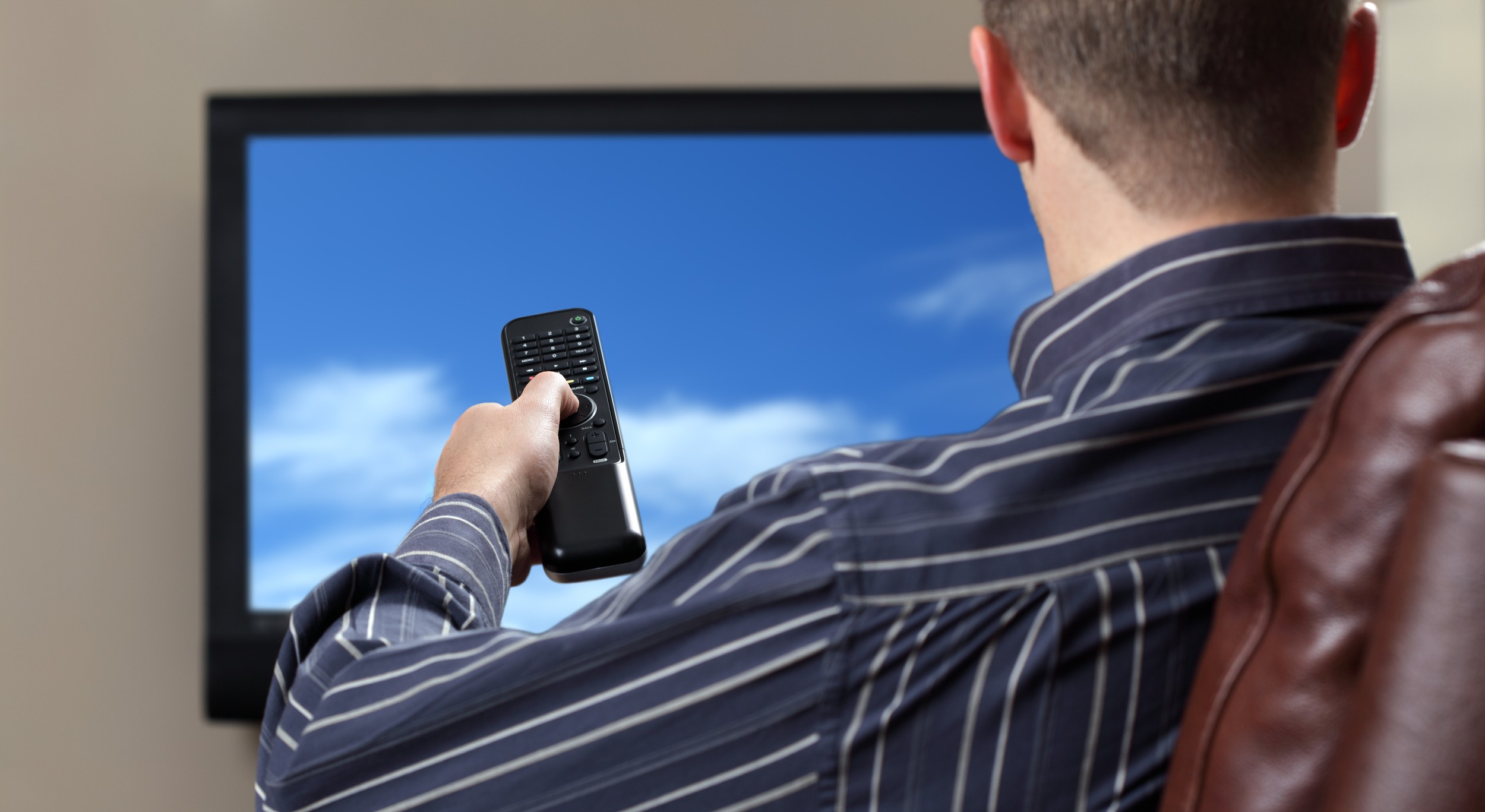 man-sitting-on-a-sofa-watching-tv-holding-remote-control-2