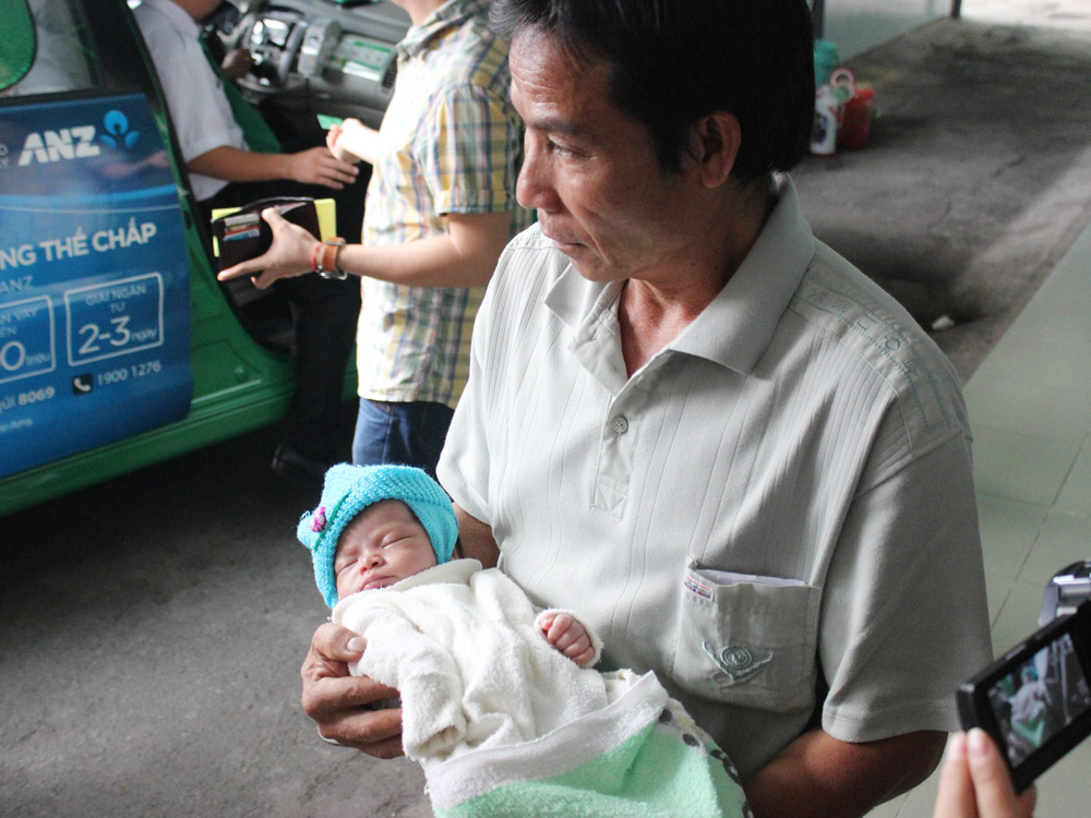 Cha nuôi bế em bé sơ sinh bị bỏ rơi dưới giếng đến Bệnh viện Nhi đồng 1 - Ảnh: Nguyên Mi