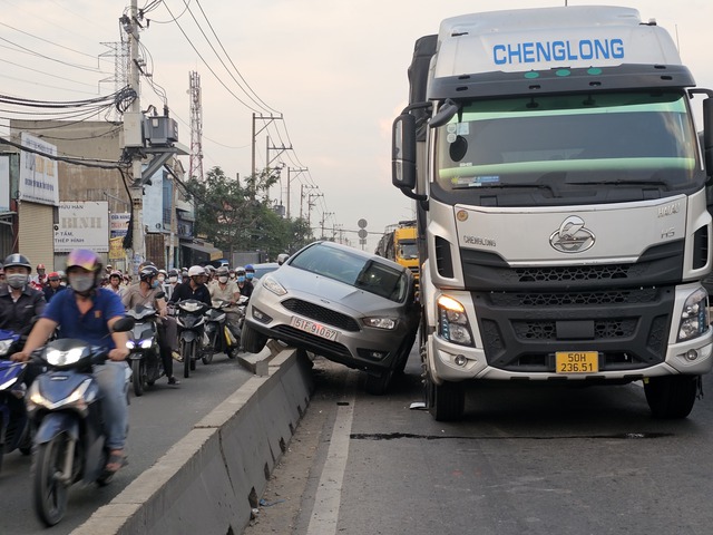 Va chạm với xe tải nặng ô tô con lao lên dải phân cách cứng - Ảnh 1.