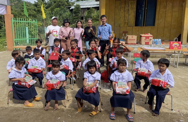 Thầy Vỹ (áo xanh) trao quà cho các em học sinh xã Trà Vinh (huyện Nam Trà My)