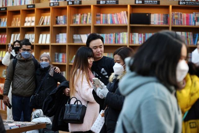 Một cặp đôi không đeo khẩu trang chụp ảnh trong trung tâm thương mại ở Seoul trong khi những người khác đeo khẩu trang hồi cuối tháng 1.2023