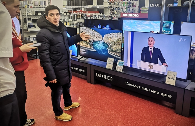 Khách hàng lựa mua tivi tại Moscow ngày 21.2 trong lúc Tổng thống Putin phát biểu