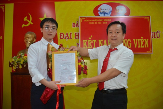 Ông Nguyễn Ngọc Nguyên, Hiệu phó Trường THPT Đầm Dơi, trao quyết định đảng viên cho Nguyễn Lê Thế Bảo (nguyên học sinh lớp 12T4, trường THPT Đầm Dơi năm học 2021 - 2022).