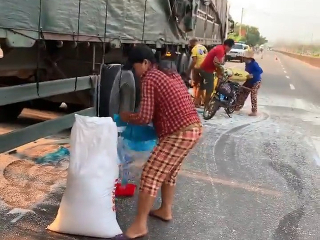 Người của nhà xe phụ giúp người dân khiêng bao gạo hốt được lên xe máy để chở đi