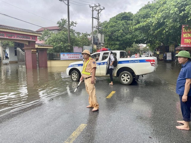 Cổng trường ngập sâu, công an dùng xe chuyên dụng đưa thí sinh vào phòng thi - Ảnh 2.