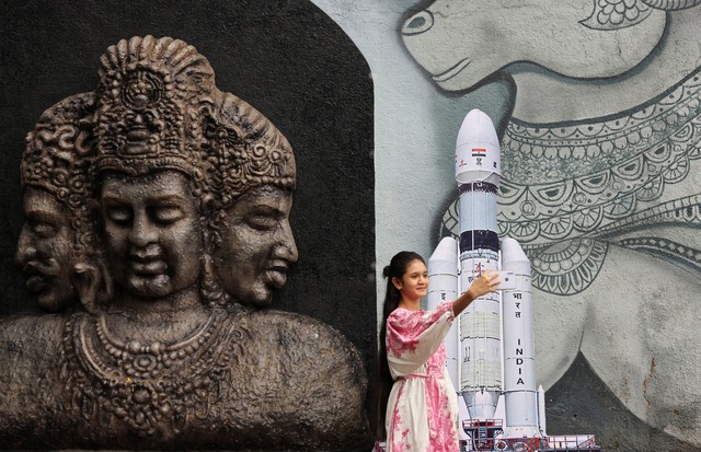 Một thiếu nữ Ấn Độ chụp ảnh bên mô hình tàu vũ trụ