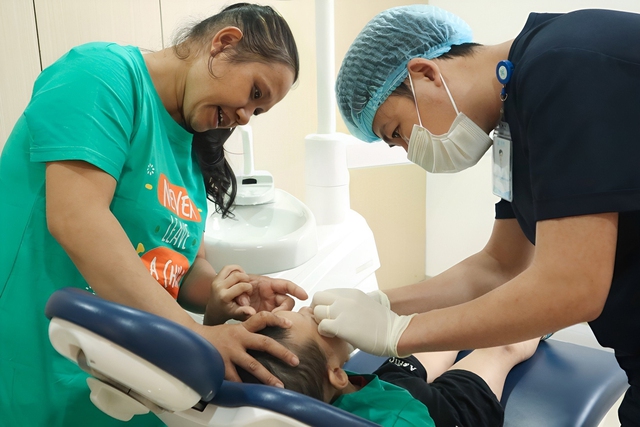 Bác sĩ thăm khám răng cho một trẻ bại não  Chú thích ảnh: CTV