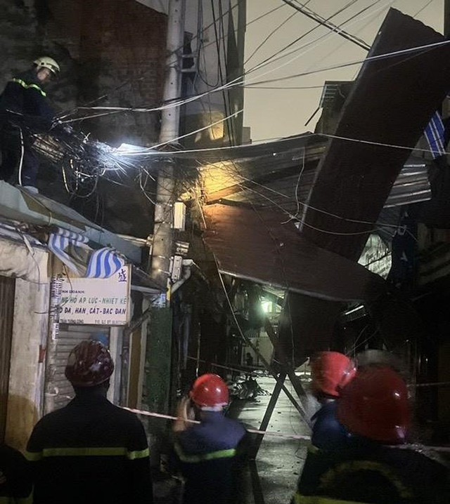 Công an cứu hộ 9 nhà dân bị tôn chung cư bay đè trong cơn mưa - Ảnh 1.