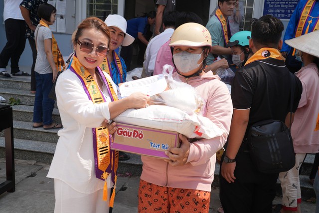 Nghệ sĩ Đức Xuân (áo trắng tay trái) trao quà cho bà con nghèo