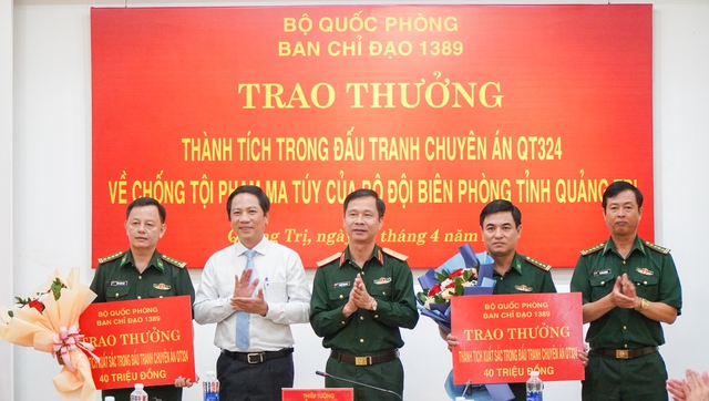 Cục trưởng Cục Điều tra hình sự, Phó trưởng ban Chỉ đạo 1389 Bộ Quốc phòng, thiếu tướng Nguyễn Thanh Huy (giữa) và ông Hoàng Nam (Phó chủ tịch UBND tỉnh Quảng Trị, thứ 2 từ trái qua) trao thưởng cho các lực lượng phá án