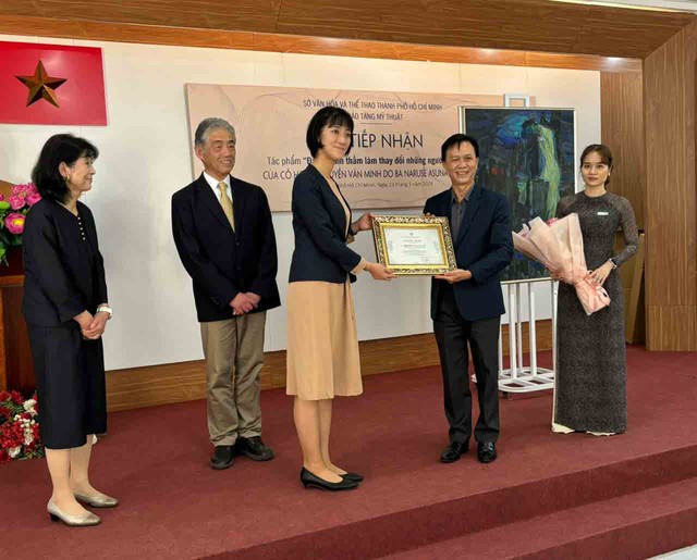 Cô Naruse Asuna nhận giấy chứng nhận hiến tặng tác phẩm Đất mẹ âm thầm làm thay đổi những người đang yêu từ ông Trần Thanh Bình, Giám đốc Bảo tàng Mỹ thuật TP.HCM. Bên trái là ông bà Naruse Tadahiro