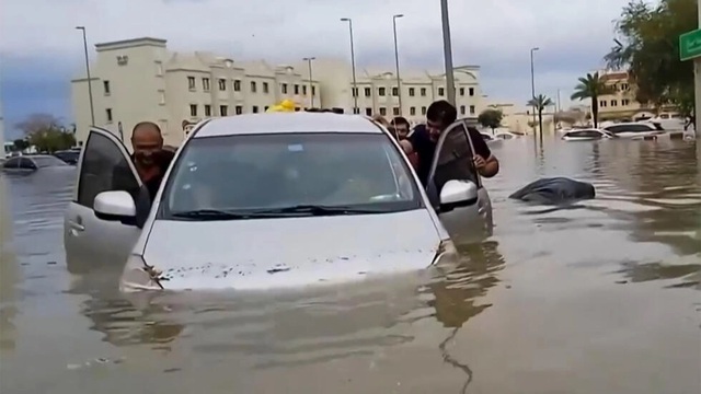 Người dân đẩy ôtô mắc kẹt trong trận lụt ở Dubai ngày 16.4