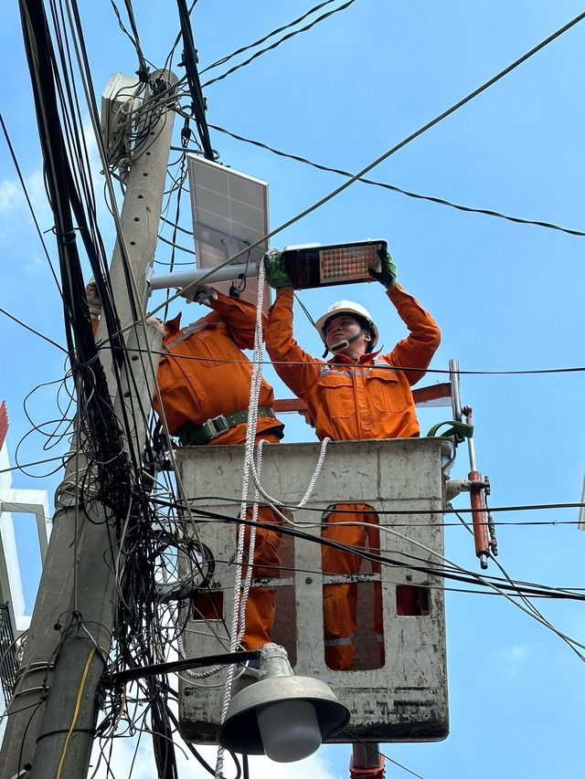 Nhân viên ngành điện lắp đặt hệ thống đèn tiết kiệm điện cho người dân TP.HCM