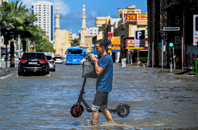 Người đàn ông băng qua đường ngập do mưa lớn ở UAE ngày 17.4