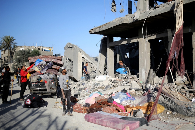 Người dân Palestine nhặt đồ từ một tòa nhà bị Israel tập kích tại thành phố Rafah ở Dải Gaza